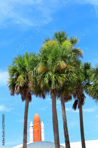 Photography Kennedy space center entrance with space rocket and palm trees over blue sky in