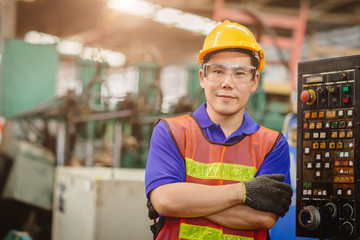Portrait of smart engineer Asian Chinese happy labor worker handsome model in heavy industry  background.arm folded cross and smiling.