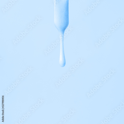 liquid blue wax or sugar paste for depilation drains from the stick on blue background. The concept of depilation  waxing  sugaring smooth skin  beauty  cream  banner  copy space  monochrome