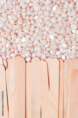 White pearl polymer wax grain seed and wooden spatula stick for depilation closeup. Concept od tools for hair remove, flyer, banner, coupon, discaunt, copy space, spa salon photo