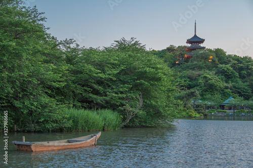 Small wooden boat on a pond in Japanese garden, three-storied pagoda behind (Yokohama, Kanagawa, Japan) photo