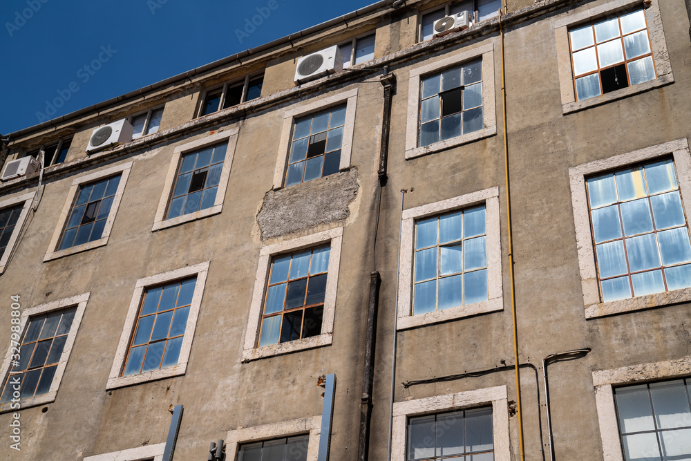 Outside of warehouse with dirty windows, peeling walls, and missing sections Outside of warehouse with dirty windows, peeling walls, and missing sections