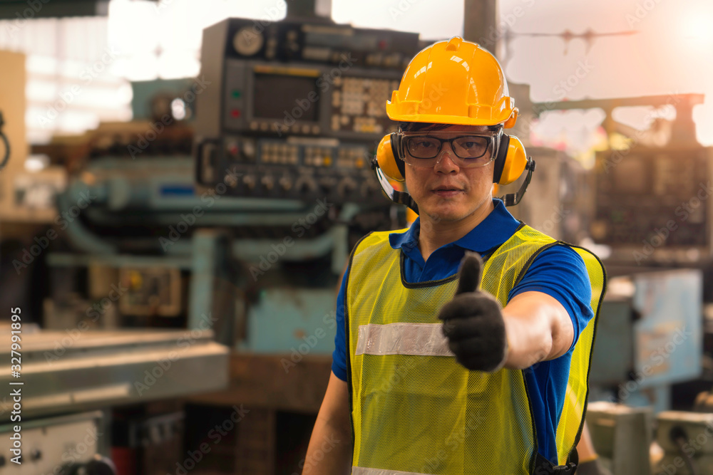 An engineer working in the the industrial. Asian portrait of a young engineer man wear a safety helmet showing thumb up. An engineer working in the the industrial. Asian portrait of a young engineer man wear a safety helmet showing thumb up.