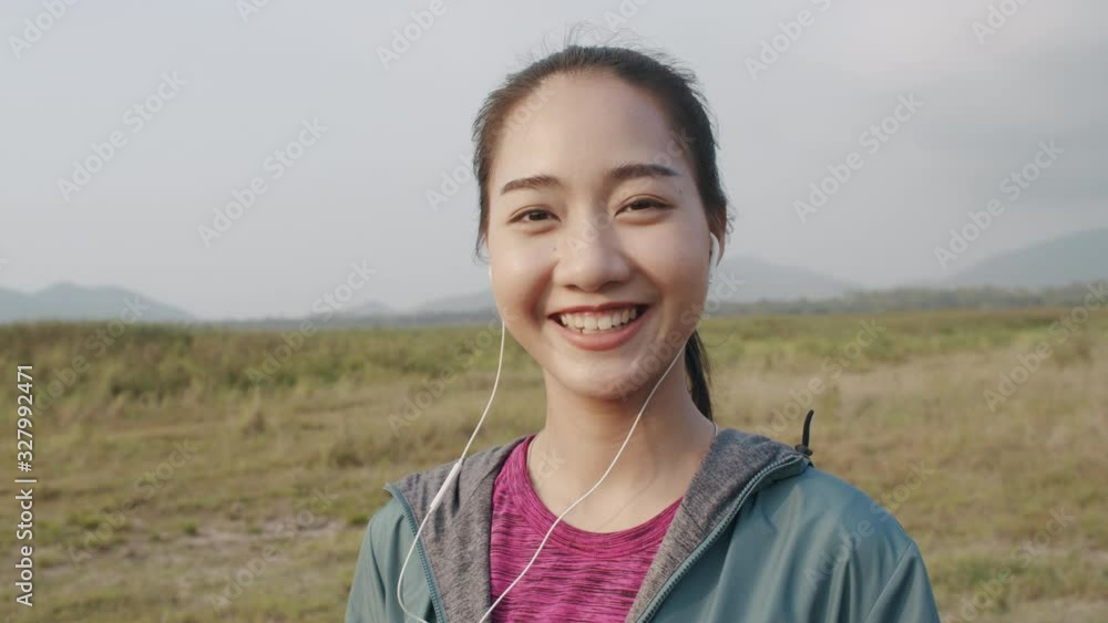 Medium close up of Asian fitness athlete women Smile and relax after a workout or running with a headphone in the summer. Close-up of the portrait on face women. Concept wellness and lifestyle Medium close up of Asian fitness athlete women Smile and relax after a workout or running with a headphone in the summer. Close-up of the portrait on face women. Concept wellness and lifestyle