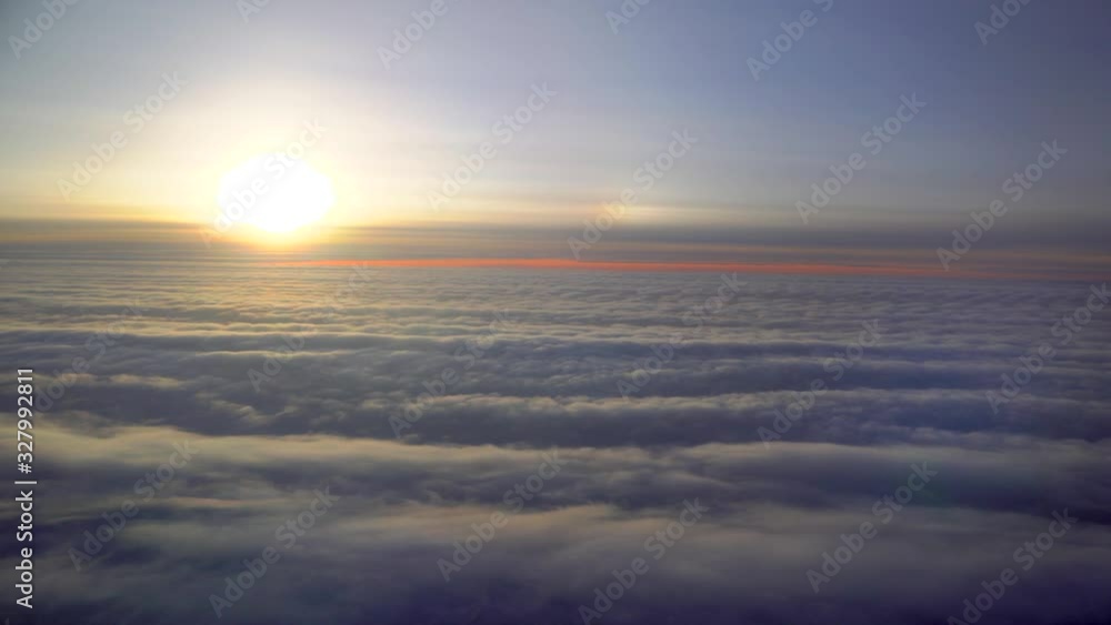Flying on an airplane. Sunrise or sunset from an airplane illuminator. An airplane wing flies through cotton clouds. The view from the window of the plane. Airplane. Travel by air. Colorful sky Flying on an airplane. Sunrise or sunset from an airplane illuminator. An airplane wing flies through cotton clouds. The view from the window of the plane. Airplane. Travel by air. Colorful sky