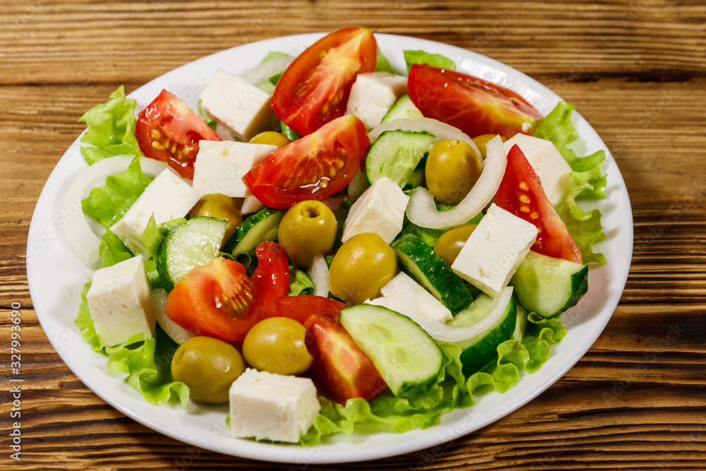 Greek salad with fresh vegetables, feta cheese and green olives on wooden table