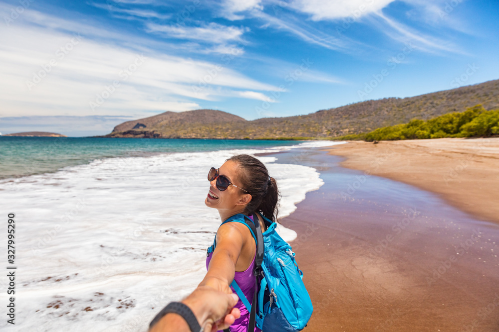 Galapagos tourist couple in follow me pose holding hands having fun on