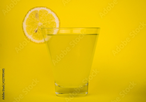  A glass of fresh lemon juice on a yellow background.