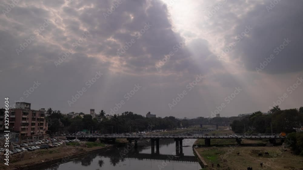 Timelapse of light pillars shining through clouds onto a busy bridge