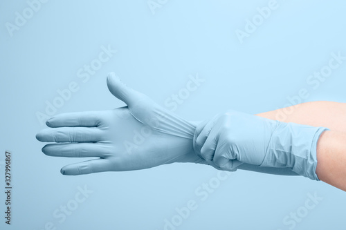 Female doctor's hands putting on blue sterilized surgical gloves photo