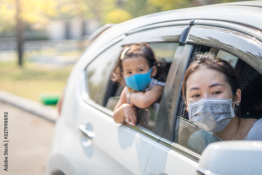 Mum and daughter wearing Medical Disposable Face Mask to prevent pollution, flu and convid-19 in car.
