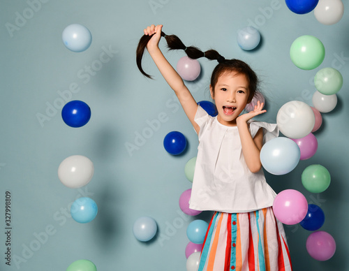 Картината върху платно Cheerful frolic asian kid girl is having fun surrounded by colorful air balloons
