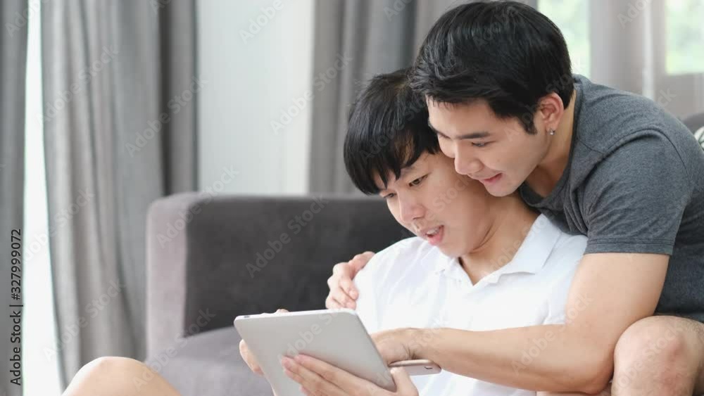 Two Asian surfing the internet using tablet and they stay in living room during morning. Two Asian surfing the internet using tablet and they stay in living room during morning.