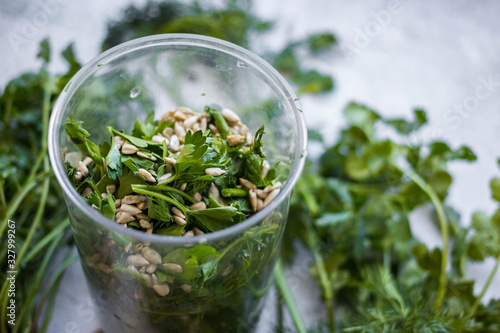 Fresh green pesto with sunflower seeds, dill, parsley, mint in glass blender jar.
