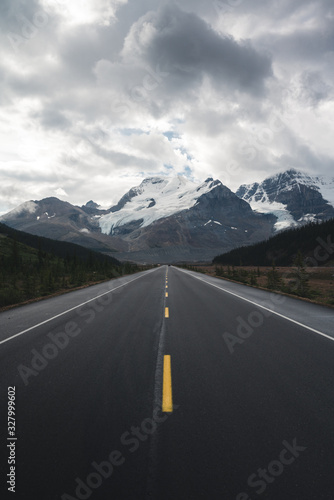Beautiful Canadian Rockies Landscape with Mountains and symmetrical road during Cloudy Summer Weather 