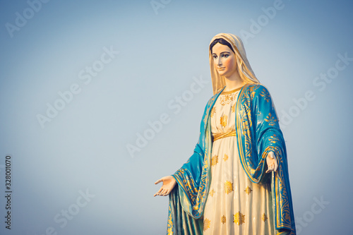 The blessed Virgin Mary statue figure. Catholic praying for our lady - The Virgin Mary. Blue sky copy space on background