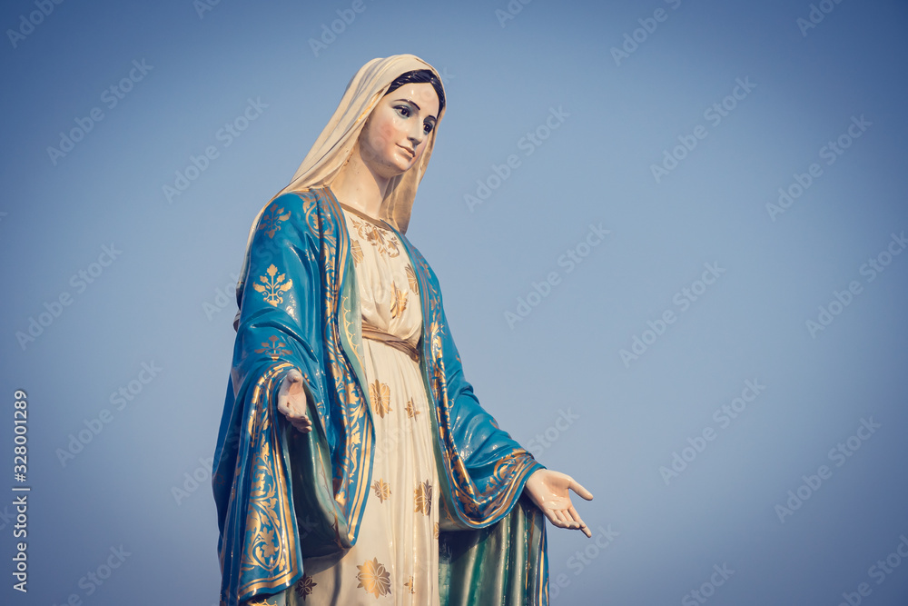 The blessed Virgin Mary statue figure. Catholic praying for our lady - The Virgin Mary. Blue sky copy space on background