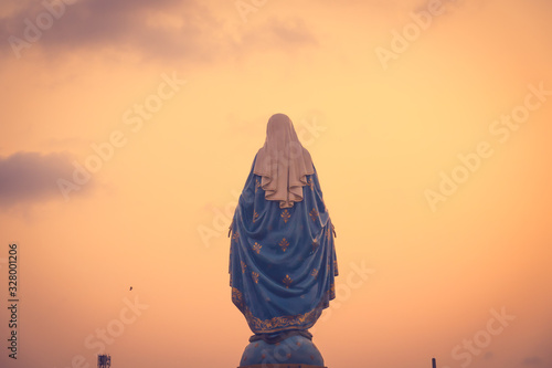 Photo The blessed Virgin Mary statue figure in a warm tone - sunset scene