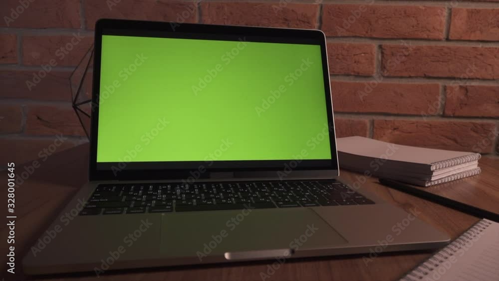 Green screen laptop for your content. Computer on table in office against background of brick wall. Camera moves. Green screen laptop for your content. Computer on table in office against background of brick wall. Camera moves.