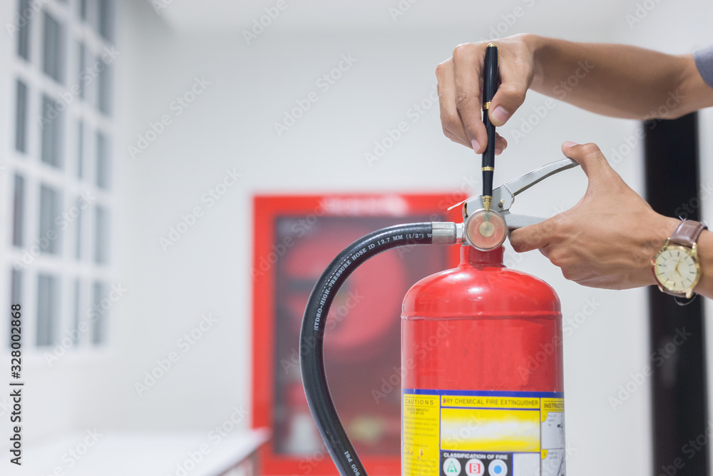 Naklejka premium Technician checking red fire extinguishers available in fire emergencies,safety concept.
