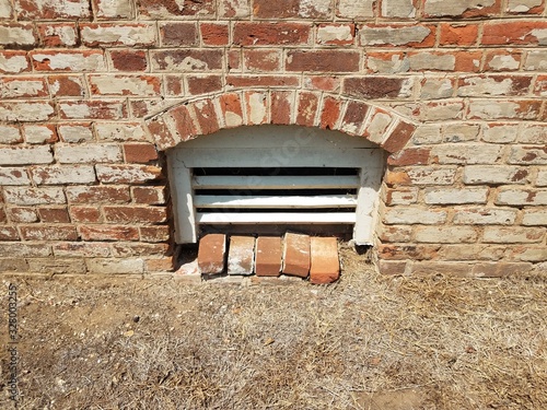 basement window with red bricks and brown grass
