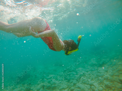 woman in red swimming suit underwater with snorkeling mask and flippers