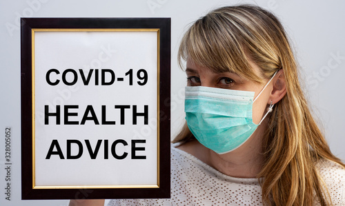 Beautiful european woman holding a frame with a COVID-19 related text Health Advice