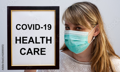 Beautiful european woman holding a frame with a COVID-19 related text Health Care