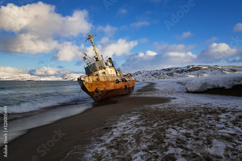 A fishing boat lying on its side, washed up by a storm on the shore of the Barents sea, the Kola Peninsula, Teriberka, Russia