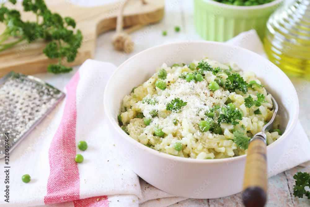 Italian cuisine. Plate of green pea risotto with green pea, parmesan cheese, olive oil and parsley Italian cuisine. Plate of green pea risotto with green pea, parmesan cheese, olive oil and parsley