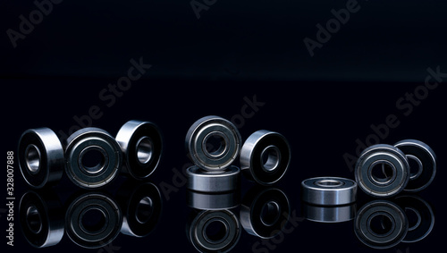Stainless steel ball bearing on balck backgroud. Set of thrust ball bearing and silver ball bearing. Spare parts for roller machine in heavy machinery and automotive industry. Round metal wheel.