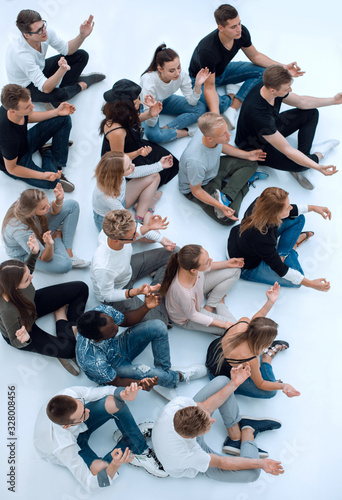 casual group of young people meditating sitting on the floor.