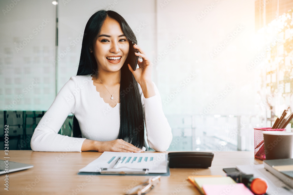 young business woman sitting at table in office talking on mobile phone and using laptop about financial and report for investment, investment concept, success concept young business woman sitting at table in office talking on mobile phone and using laptop about financial and report for investment, investment concept, success concept
