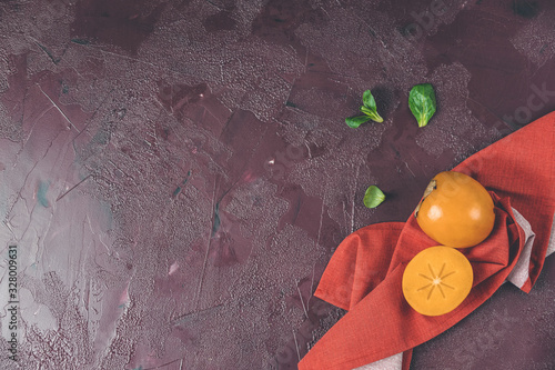 Healthy food background with persimmon and doucette (lambs-lettuce, cornsalad, field salad) with napkin on a red background, top view flat lay. photo