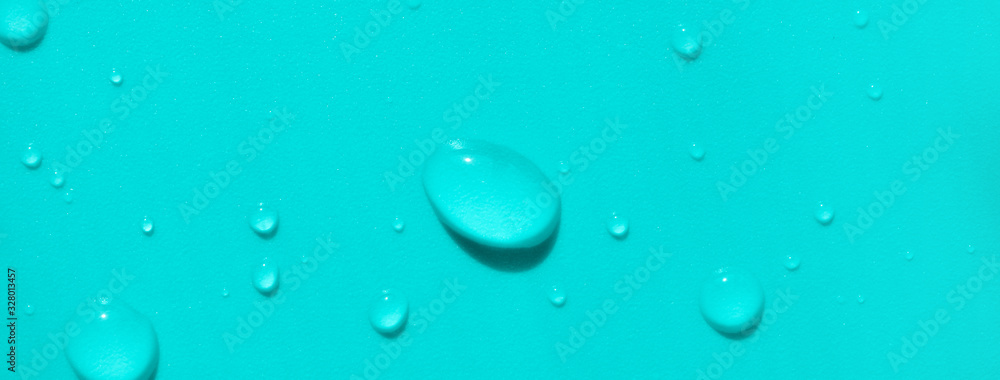 Close-up water drops on turquoise colored background, top view. Banner format backdrop
