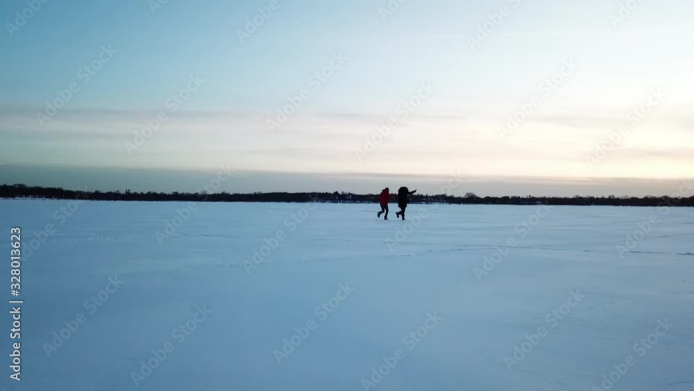 two person running in snow during blue hour, frozen lake in Minnesota two person running in snow during blue hour, frozen lake in Minnesota