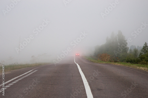 The car on the road in thick mist. Danger driving