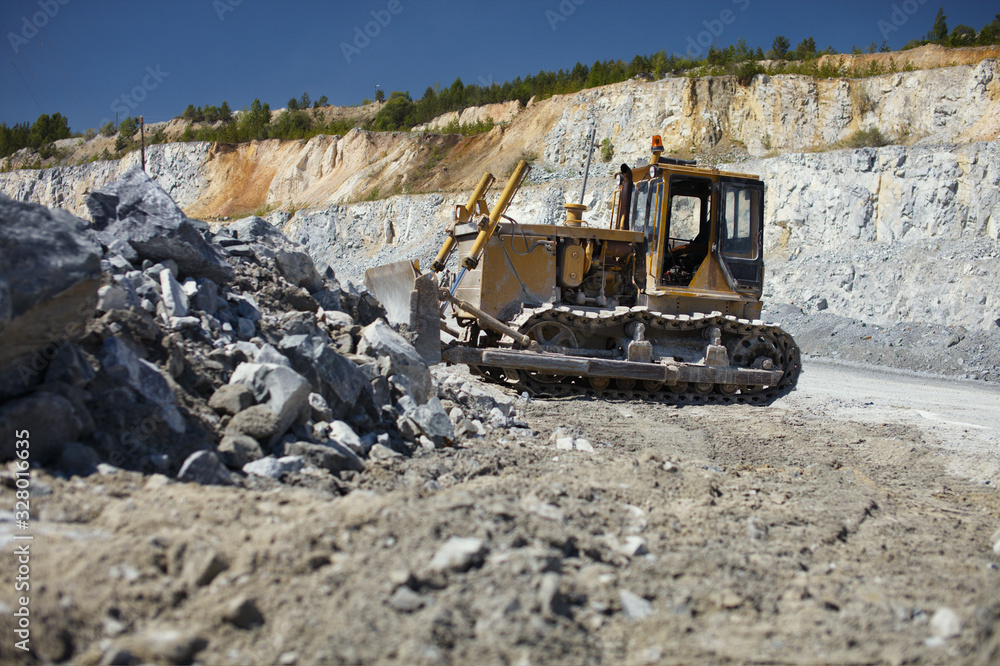 Old rusty bulldozer on the background of the quarry and fragments of stone ore. Old rusty bulldozer on the background of the quarry and fragments of stone ore.