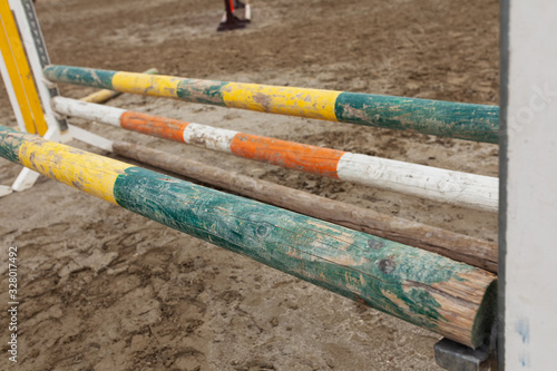 Colorful horse jumping barriers knocked down and collapsed in sand, old and dirty