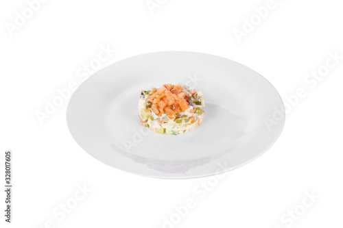 Russian salad with red fish, chum salmon, eggs, cucumbers, carrots, potatoes on plate, side view white isolated background