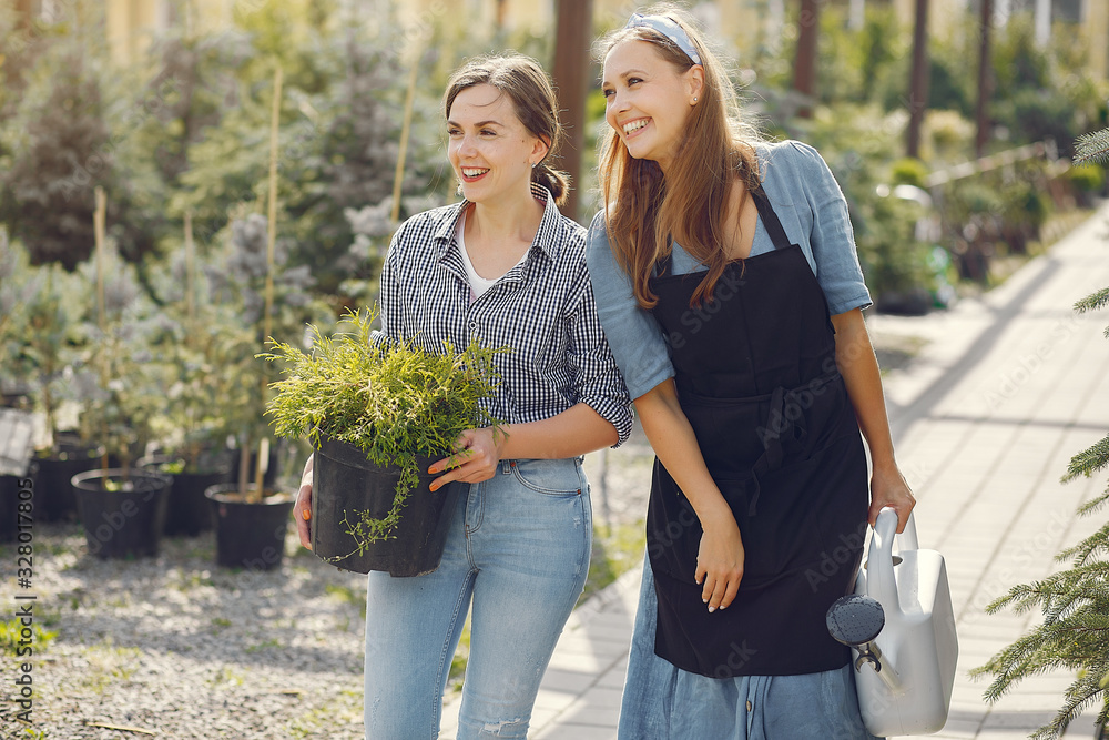 Women in a greenhouse. Lady working with a flowerpoots. Girl in a black apron.