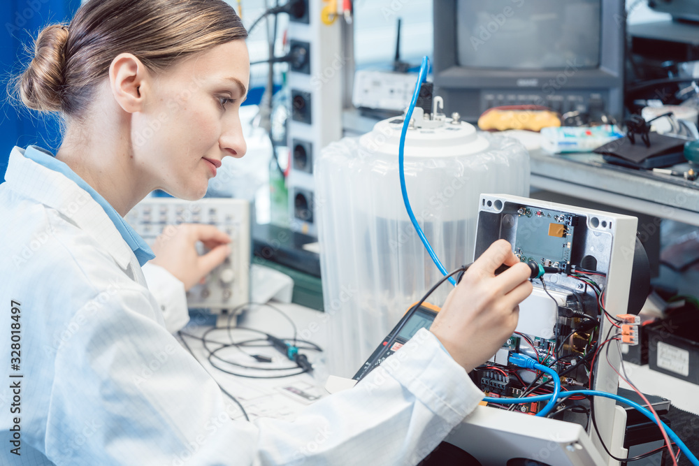 Engineer woman measuring electronic product on test bench - obrazy, fototapety, plakaty 