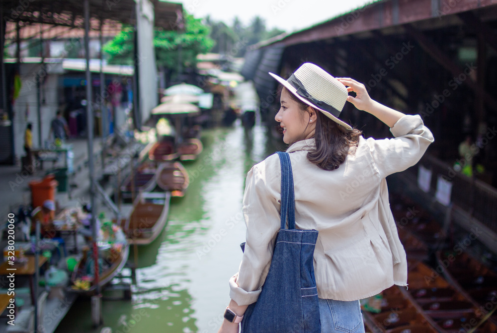 asia female tourists wearing hat holding camera and smartphone take photo vlog live . Beautiful woman visiting Damnoen Saduak floating market,Ratchaburi.