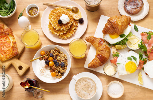 Top view image of brunch menu on wooden table. Healthy sunday breakfast with croissants, waffles, granola and sandwiches. Flatlay with tasty food photo