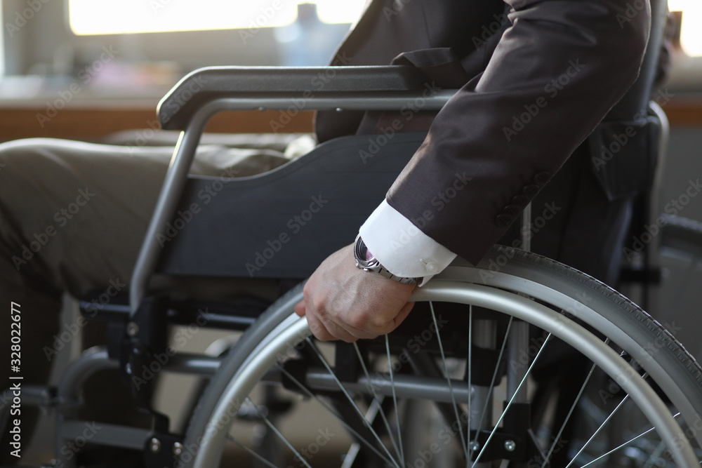 Obraz premium Close-up of disabled man on wheelchair in office wearing presentable suit. Adaptation of people with disabilities in society. Recovery and healthcare concept