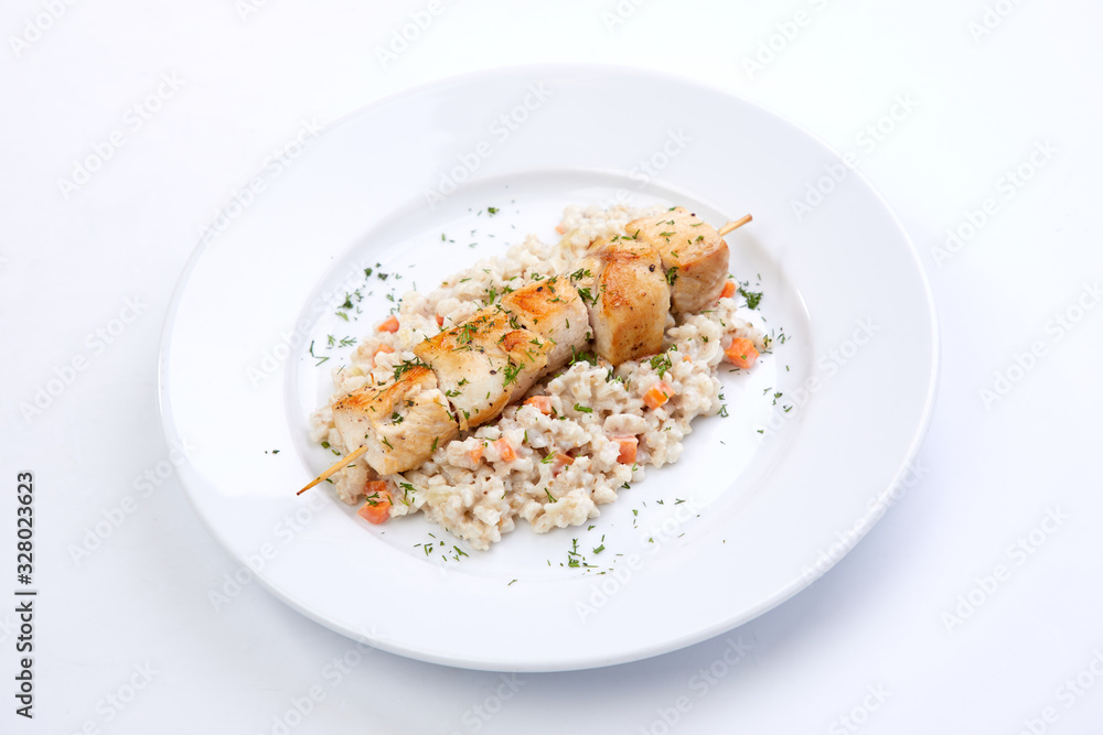 chicken kebab with barley on the white plate