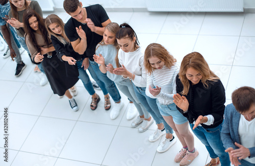 diverse young people standing in a row and pointing to a copy of the space