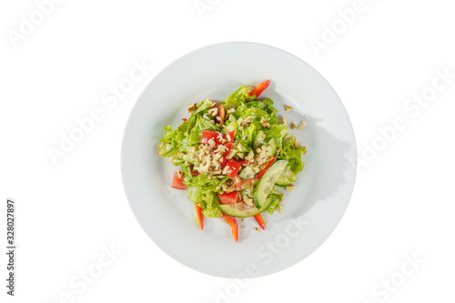 Caesar salad with pieces of chicken breast, tomato, bell pepper, cucumber, lettuce, walnuts on plate, white isolated background, view from above. For the menu, restaurant, bar, cafe