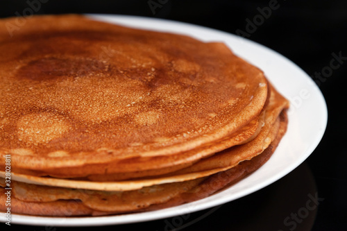 A stack of delicious hot and fresh thin pancakes baked in a pan of milk, flour and eggs for breakfast at home. Russian national holiday Shrovetide.