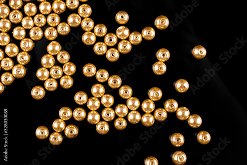 A scattering of yellow pearl beads on a black background